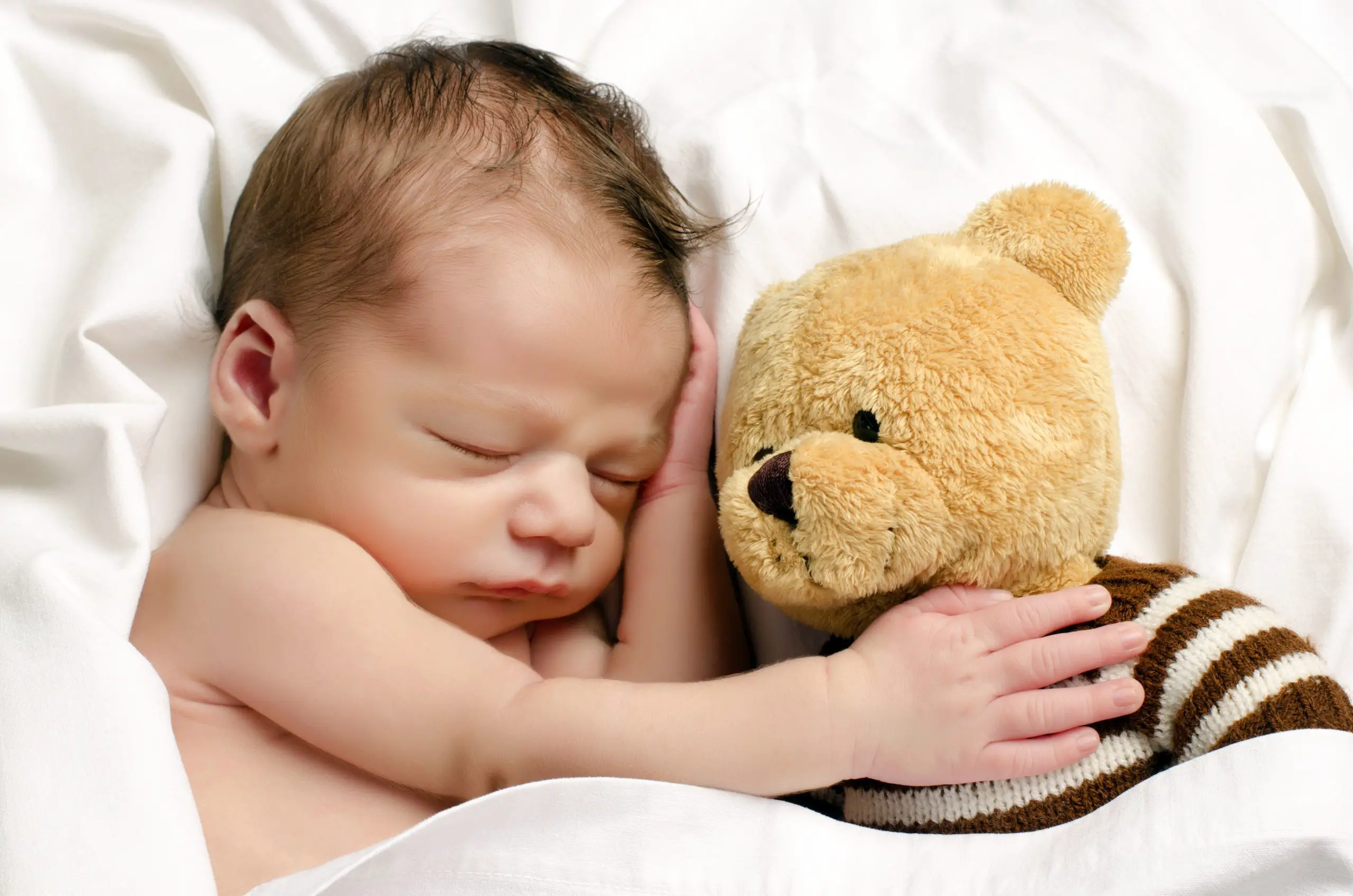 Sleeping baby hugging a teddy