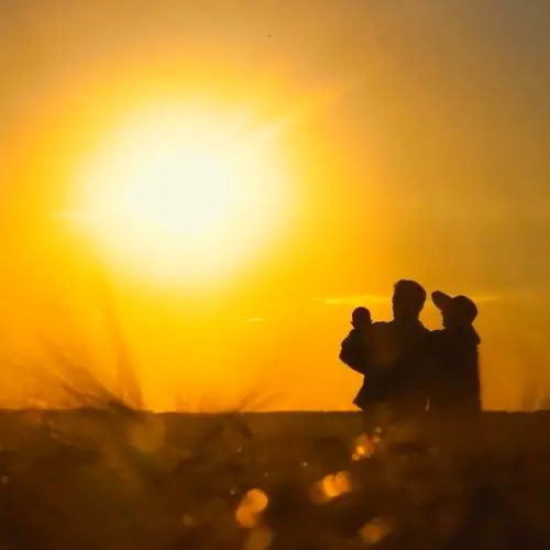 father with wife and baby watching the sunset