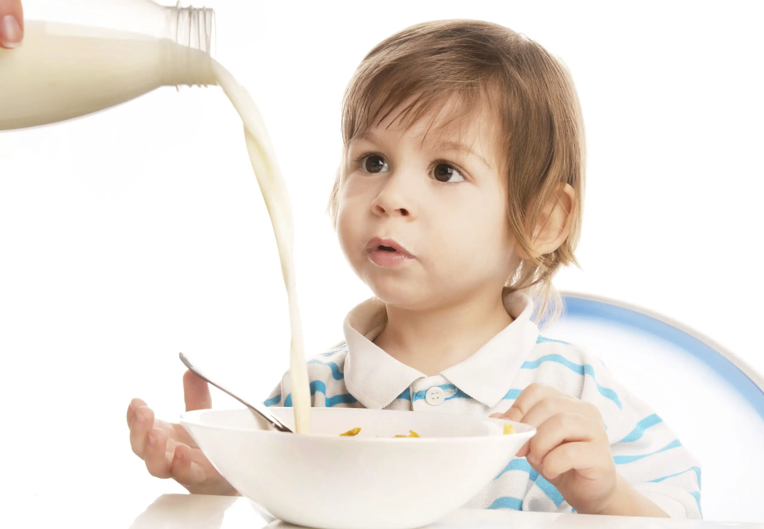 toddler staring at the poured milk on his bowl