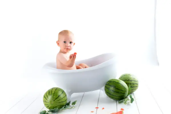 baby on a hot tub eating watermelon