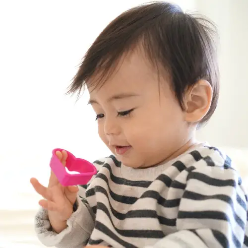 Smiling toddler holding a heart shaped toy