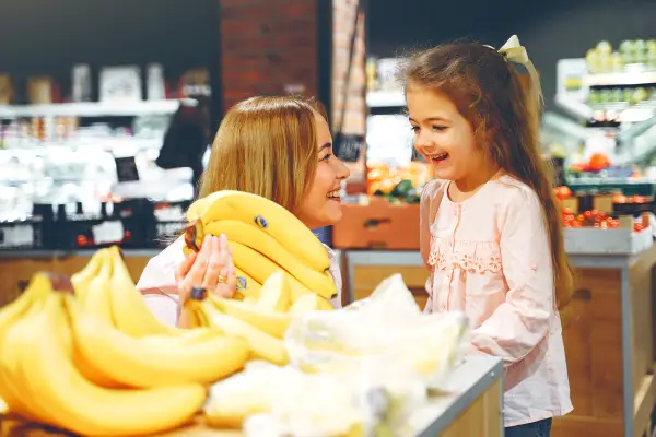 Mom and baby girl buying bananas