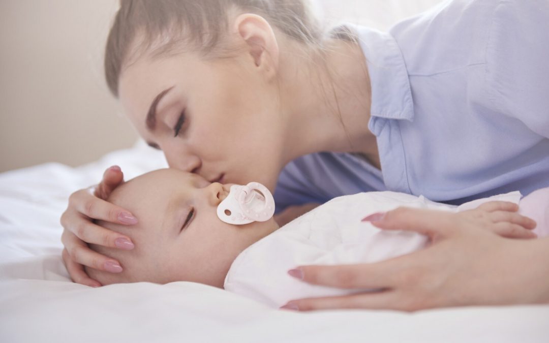 Young mom kissing her sleeping baby