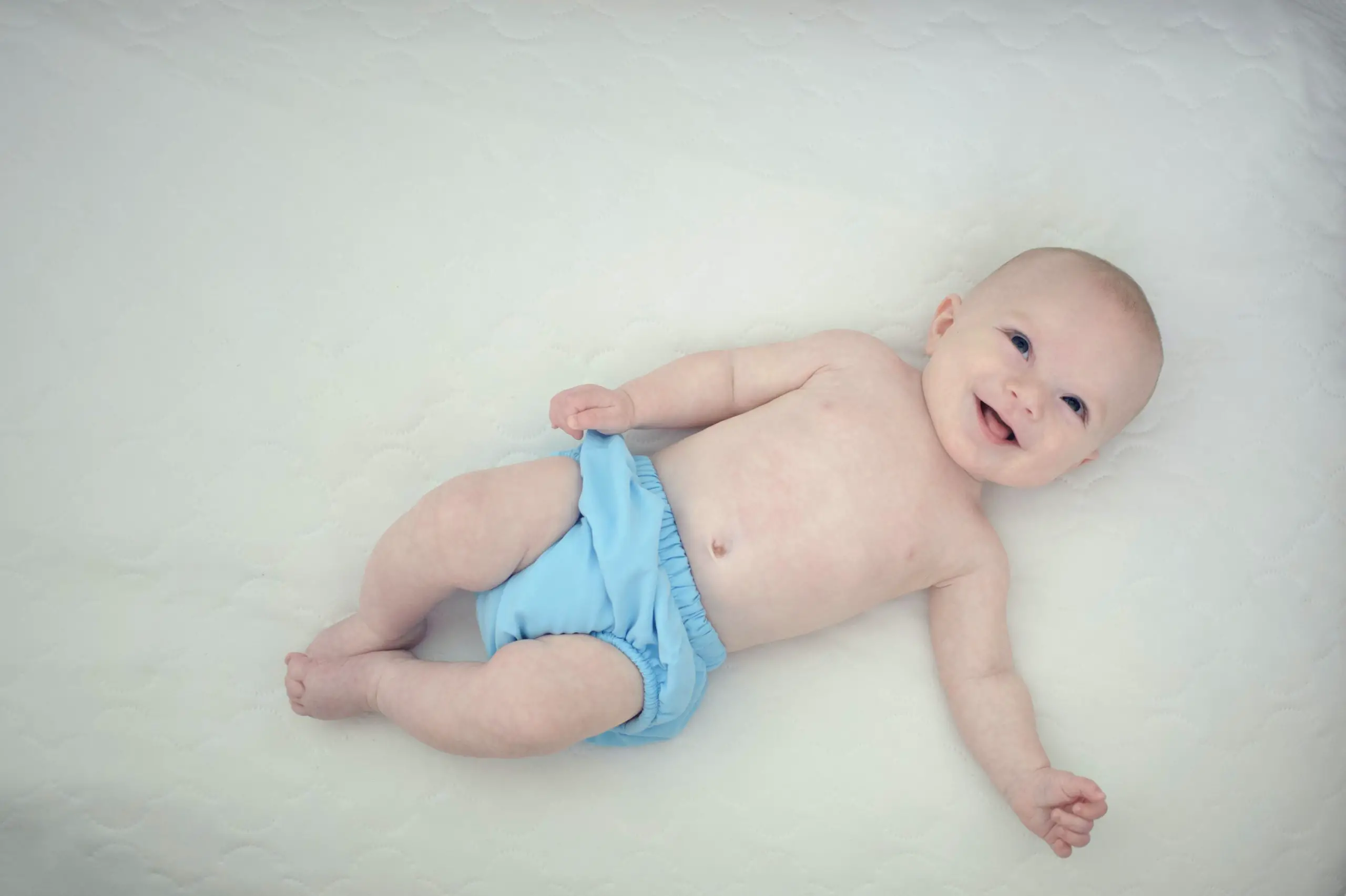 smiling baby wearing a blue cloth diaper